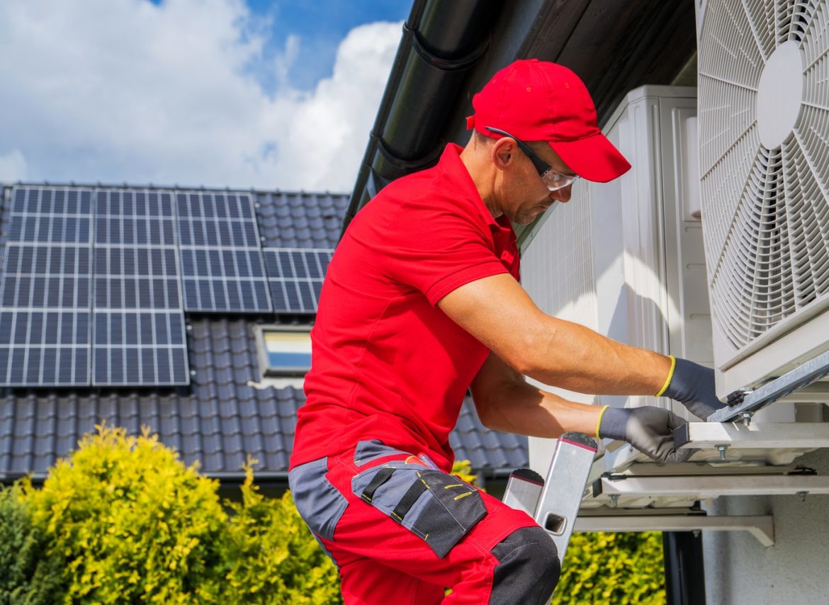 HVAC Worker Performing Heat Pump Maintenance. Device is Transferring Thermal Energy From the Outside Using the Refrigeration Cycle. Home Heating Technologies.